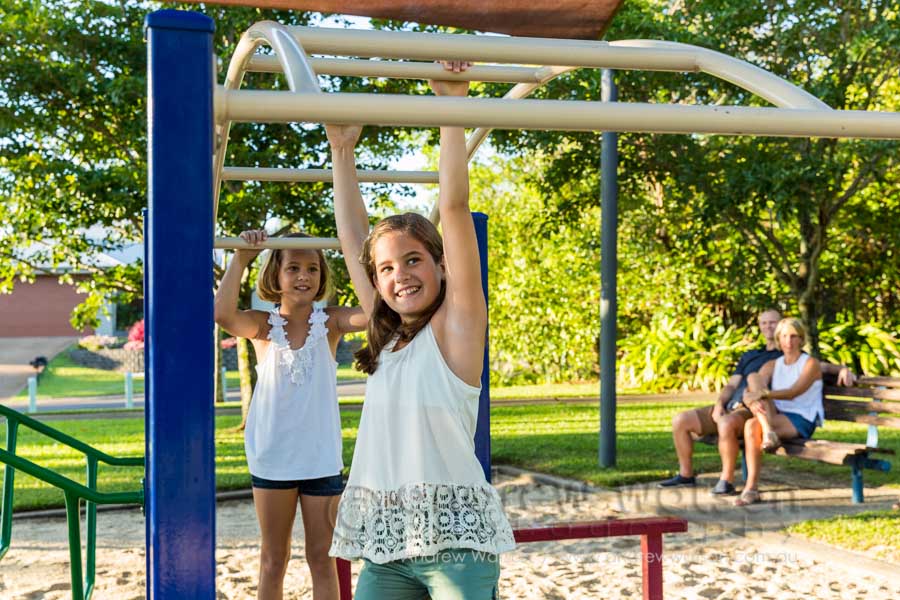 Lifestyle image of kids playing in playground with parents looking on