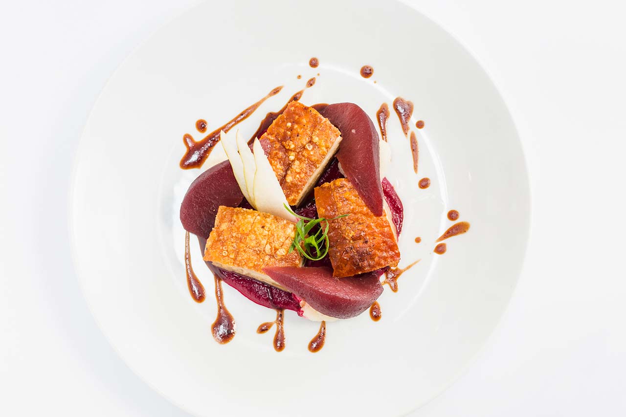 Image of French-style pork belly dish with red wine poached pear