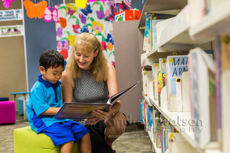 Image of teacher reading a book to a young student