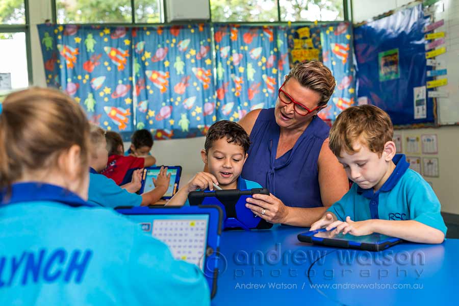 Image of school teacher helping young student using iPad