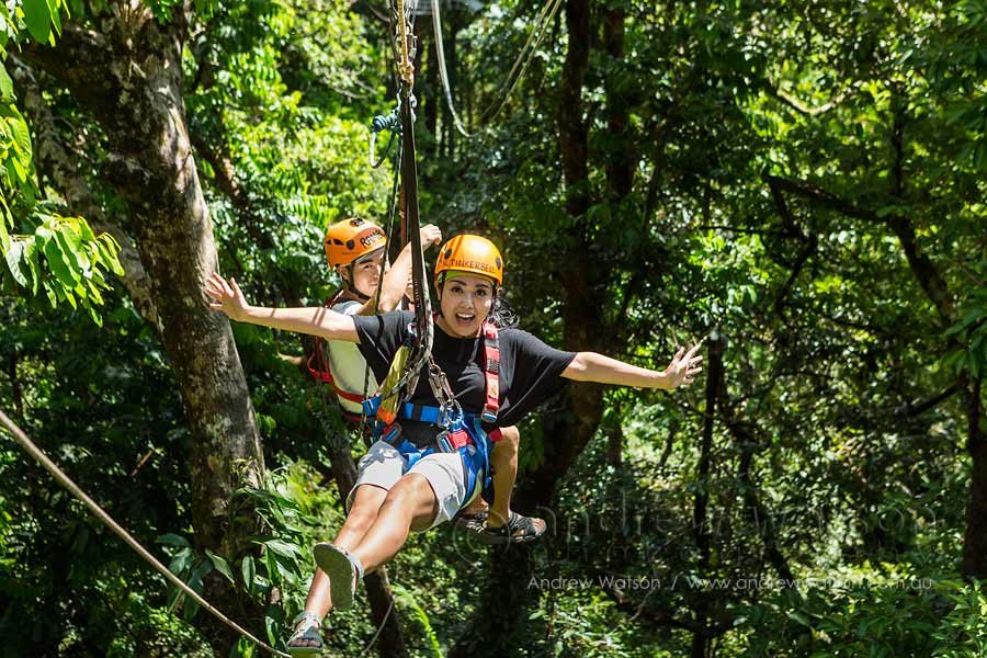 Couple having fun moving between platforms on rainforest canopy zipline