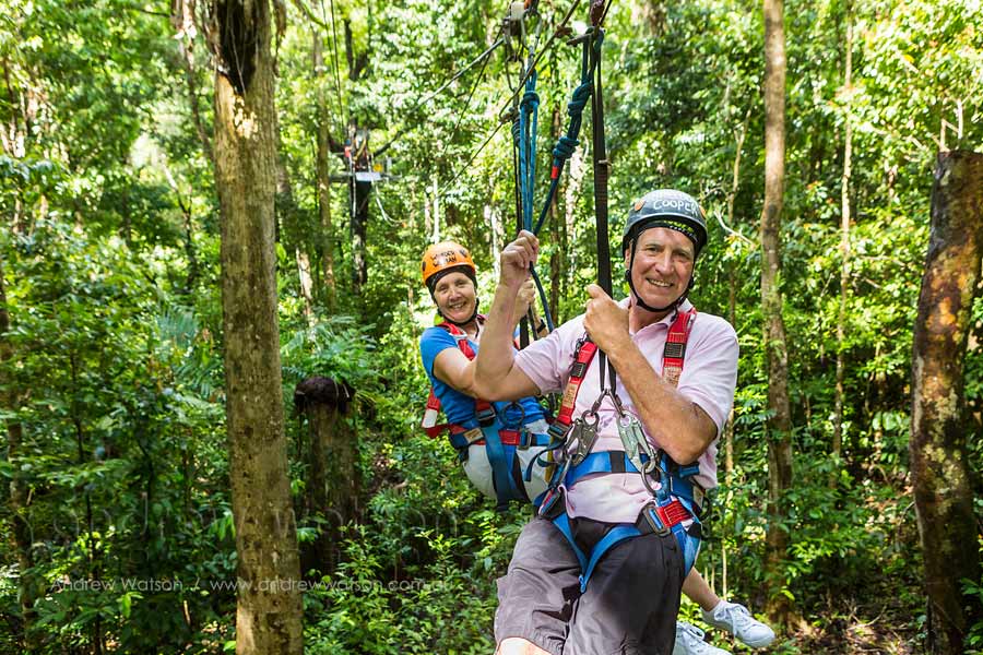 Older couple ziplining through rainforest canopy
