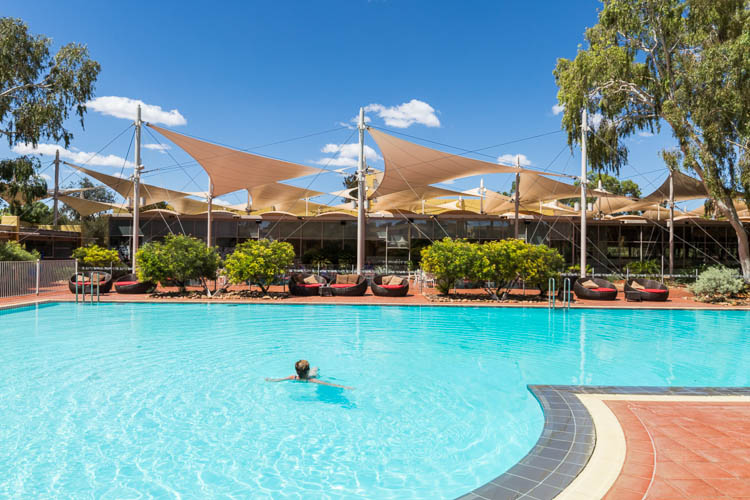 Image of guest swimming in the outdoor pool at Sails in the Desert Hotel