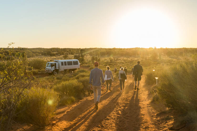 Image of guests walking through the desert at sunrise