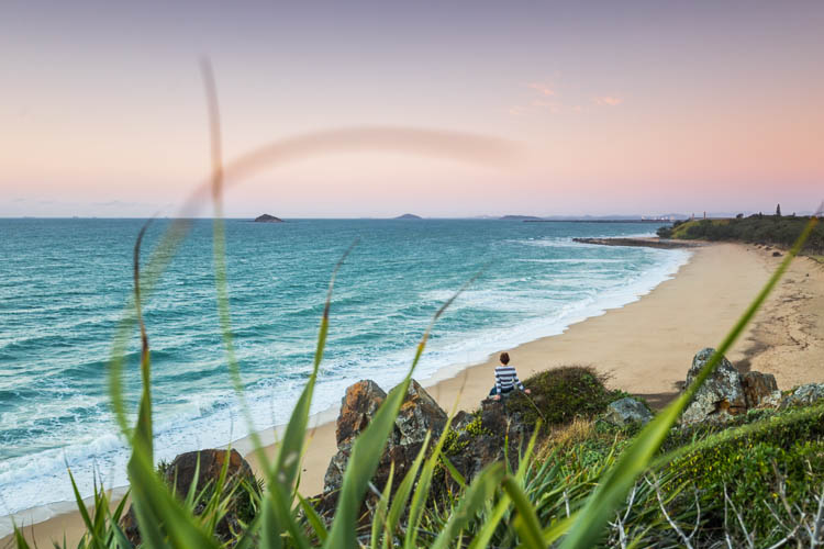 Image of woman looking out on Lamberts Beach at dawn