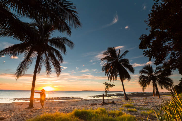 Image of visitor standing amidst coconut palms at Clairview Beach
