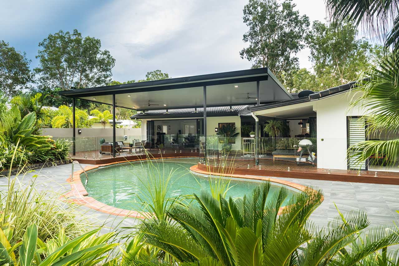 View through foliage to pool and outdoor entertaining area of Kewarra Beach residence