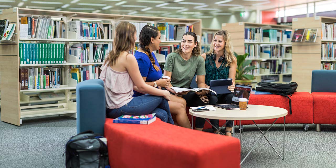 A group of TAFE students discussing a project whilst sitting in the library