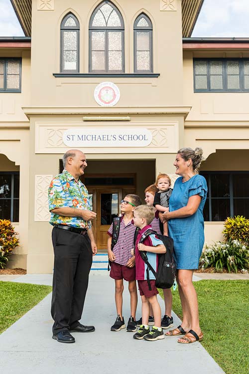 School teacher talking to parent and her children in front of school building