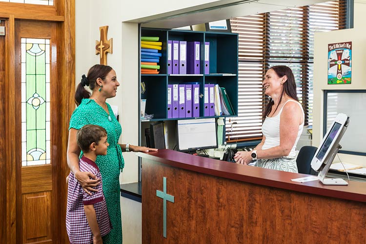 Parent and child talking to school reception in catholic school