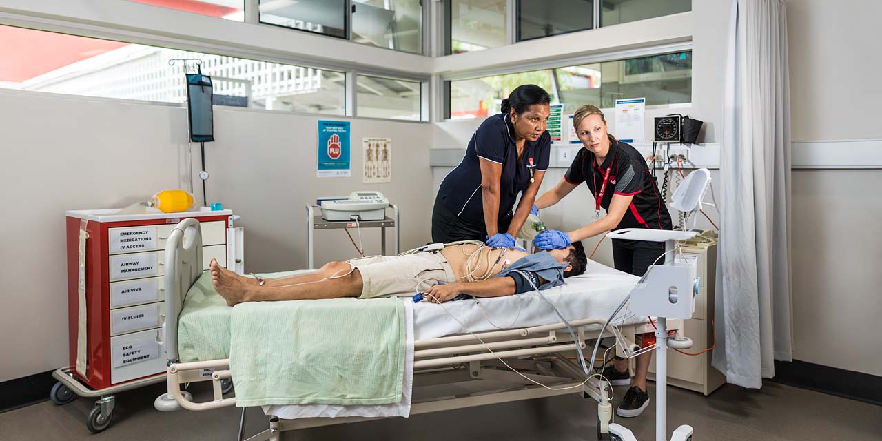 Nursing student practicing CPR on patient with teacher assisting