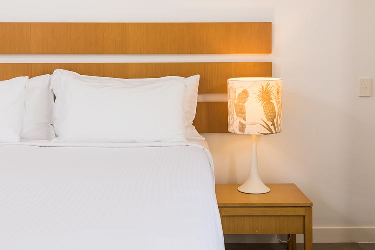 Hotel bed and bedside lamp at Port Douglas resort