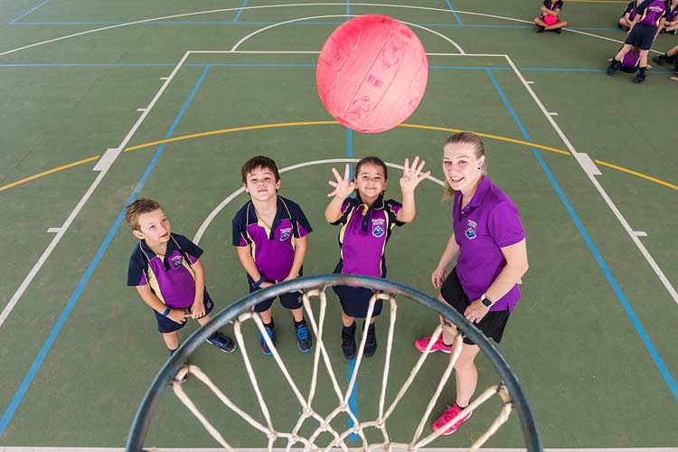Group of young students and teacher learning to shoot at netball