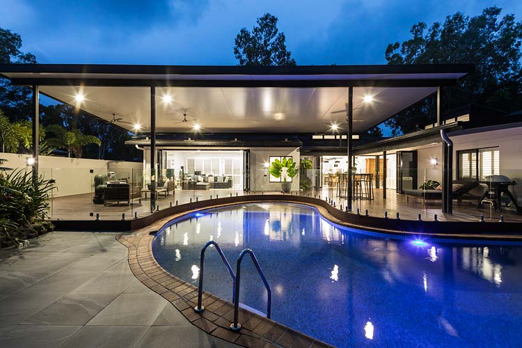 Pool and outdoor entertaining area of residential home illuminated at twilight