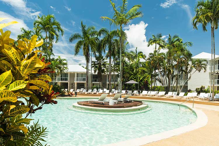 Resort swimming pool surrounded by palms and sun lounges