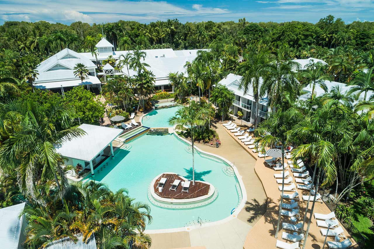 Aerial view of resort pool surrounded by sun lounges and umbrellas