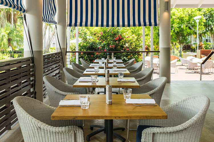 Restaurant tables and chairs with view to tropical surrounds