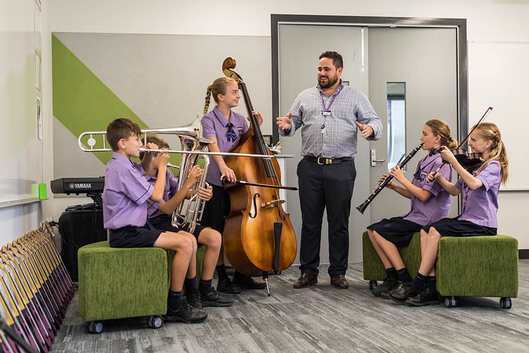 A teacher leading school students in band practice playing instruments