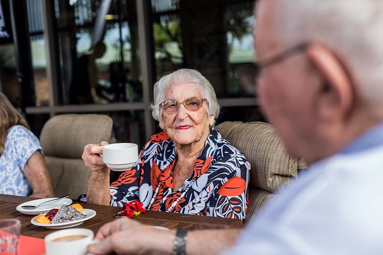 Portrait of a female resident enjoying morning tea at an aged care home