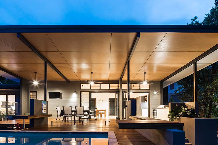 Pool and entertaining deck of residential home illuminated at twilight