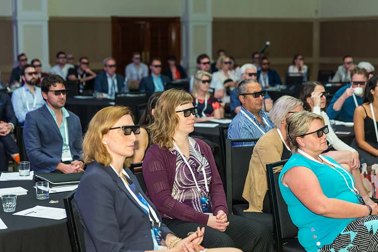 Delegates with 3D glasses on watching a speaker at medical conference
