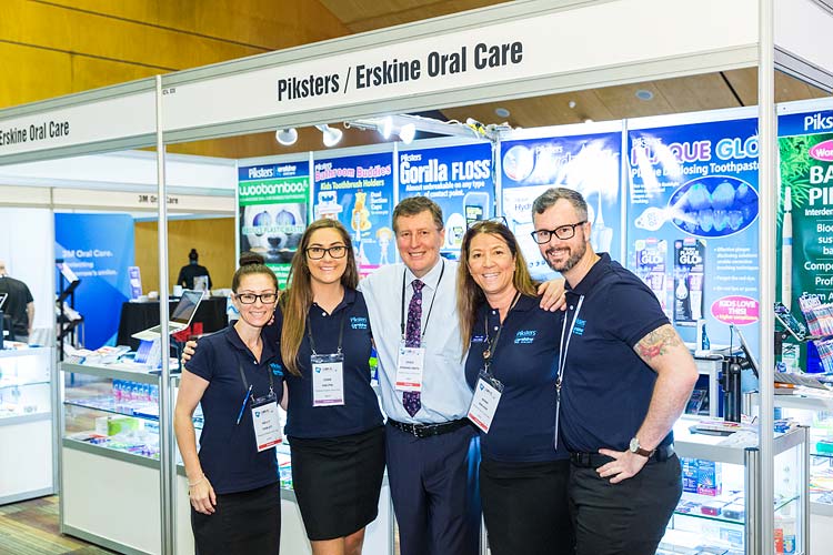Dental suppliers standing in front of booth at conference tradeshow
