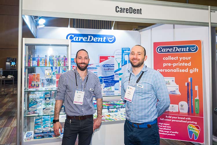 Two dental suppliers standing in front of booth at conference tradeshow