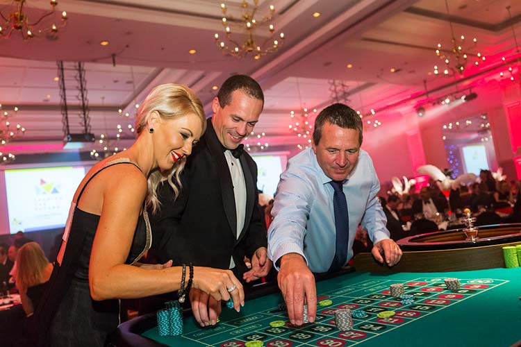 People placing bets on roulette table at gala dinner