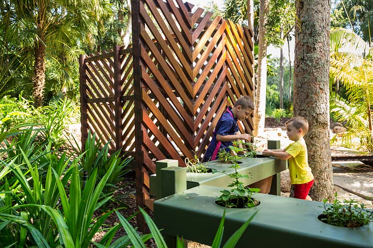 Kids touching and feeling herbs in an outdoor sensory playground
