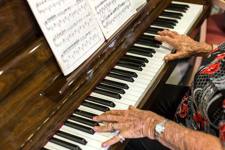 Hands playing a piano at a residential aged care home