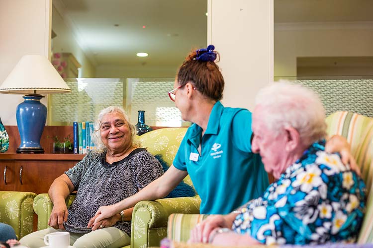 A residential aged care worker talking to seated residents