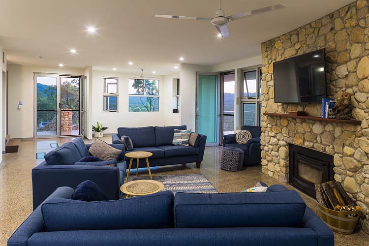 Interior of the Walsh River House showing living area with feature stone wall and fireplace