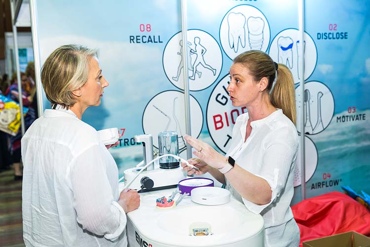 A tradeshow supplier showing off dental equipment to conference delegate