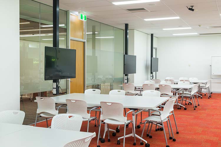 Interior of the James Cook University library showing collaborative learning space tables and screens