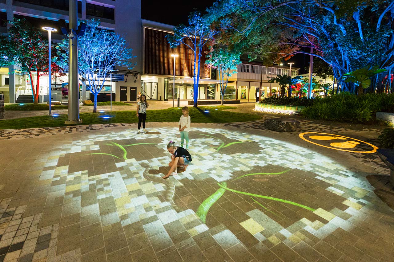 Kids interacting with an indigenous artwork digitally projected on the footpath in the Shields Street Heart Project, Cairns