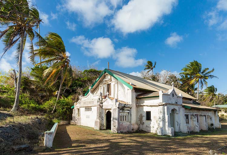 An old missionary church on Erub Island surrounded by coconut palms