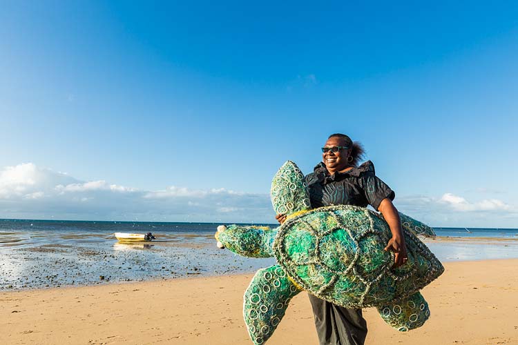 Portrait of an Erub Island woman holding a turtle artwork made from abandoned fishing nets