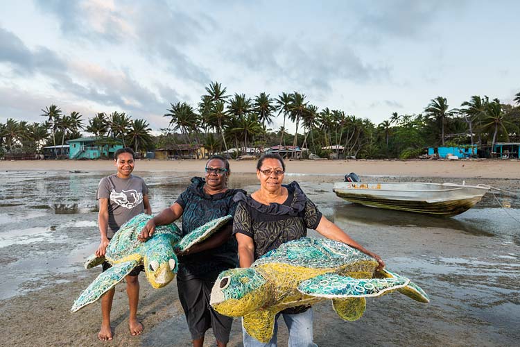Portrait of Erub Island women holding turtle artworks made from abandoned fishing nets