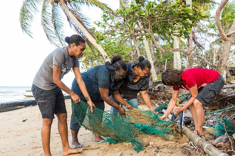 A group of women emoving fishing nets washed ashore on Erub Island