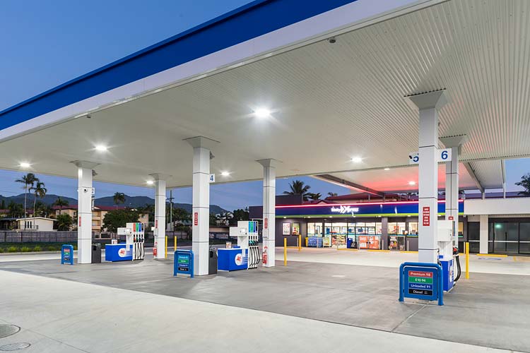 Fuel pump forecourt and convenience store of service station illuminated at twilight
