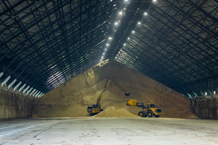 Interior of a sugar shed showing machinery loading raw sugar into underground hoppers