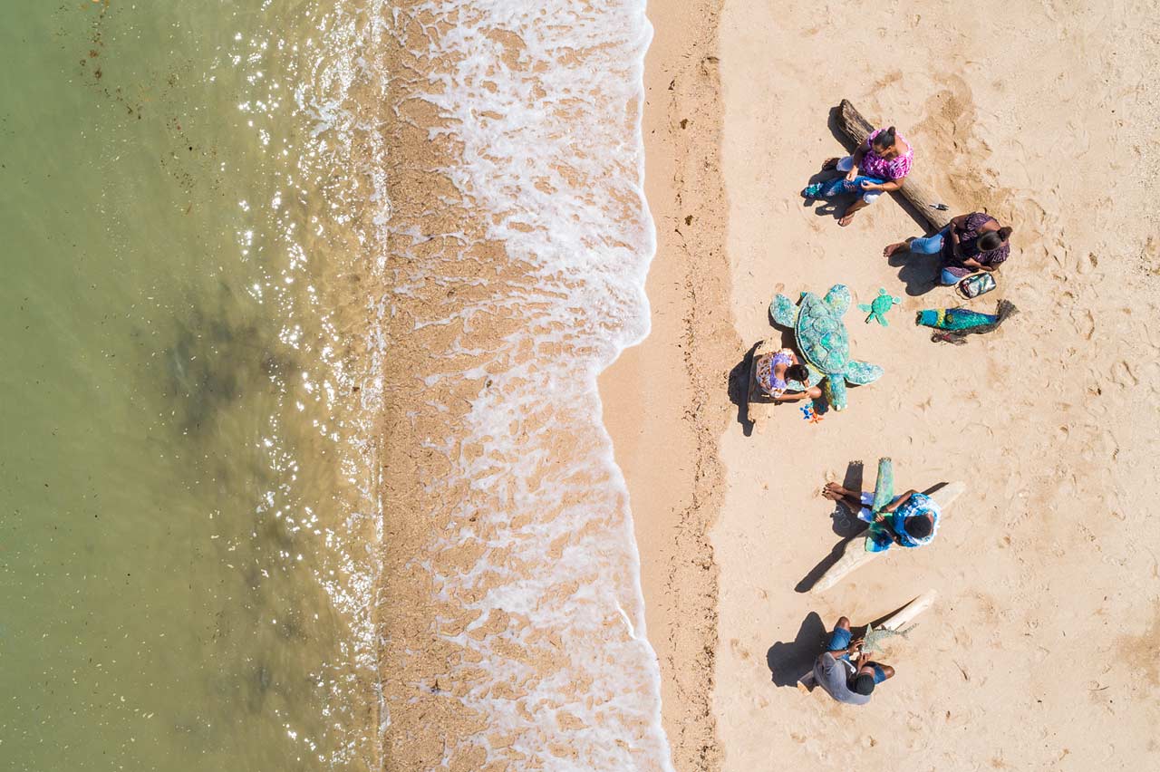 Aerial view of Erub Island artists working on ghost net artworks on the beach