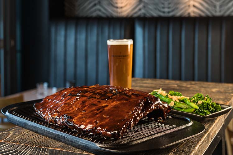 A dish or barbequed pork ribs rack, beer and sides