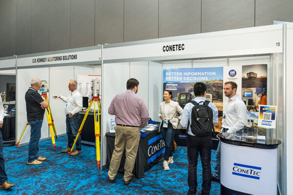 People talking in front of trade exhibit booths at conference