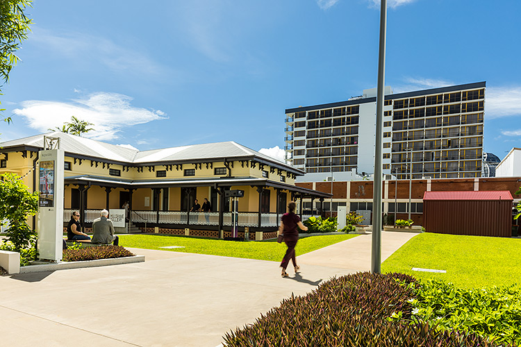 People seated outside the rear of Mulgrave Gallery building on the Cairns Esplanade