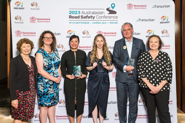 Group photo of award winners holding their awards against media wall
