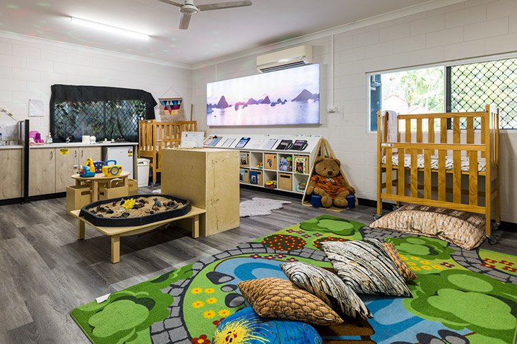 A baby sleep room in an early learning centre with cots, books and soft spaces