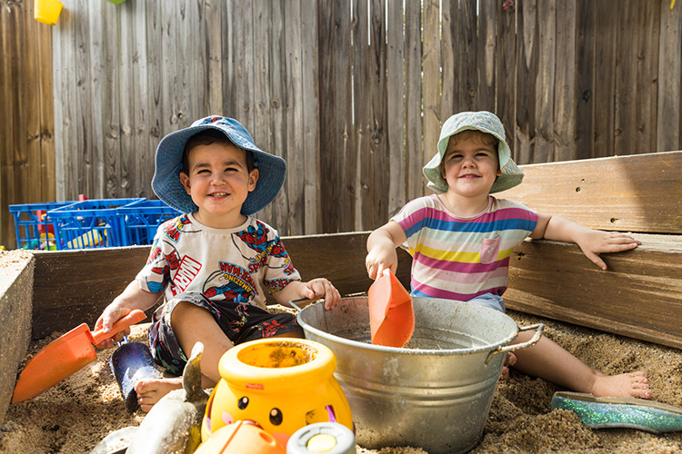 Portrait of a boy and girl playing in a sandpit at an early childhood centre