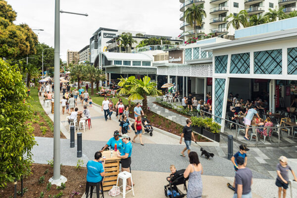 People walking and seated along Esplanade promenade with restaurant diners in background