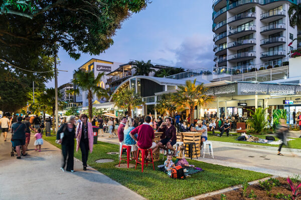People walking and seated along Esplanade promenade with restaurant diners in background